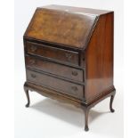 A walnut bureau with fitted interior enclosed by fall-front above three long graduated drawers, & on