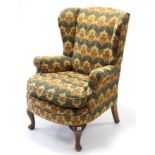 A Victorian wing-back armchair upholstered multi-coloured foliate material, & on short cabriole legs