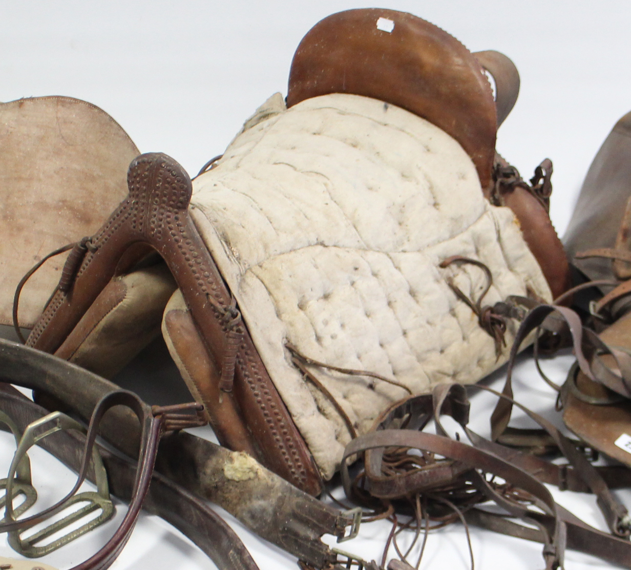 Three leather horse riding saddles; two pairs of riding breeches; a woven horse-hair riding crop;