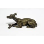 A bronzed ornament in the form of a recumbent greyhound with articulated jaw & with legs crossed (