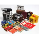 A Braun “Paxette” 50mm camera; a Kodak “Brownie Reflex” box camera; & various camera accessories.