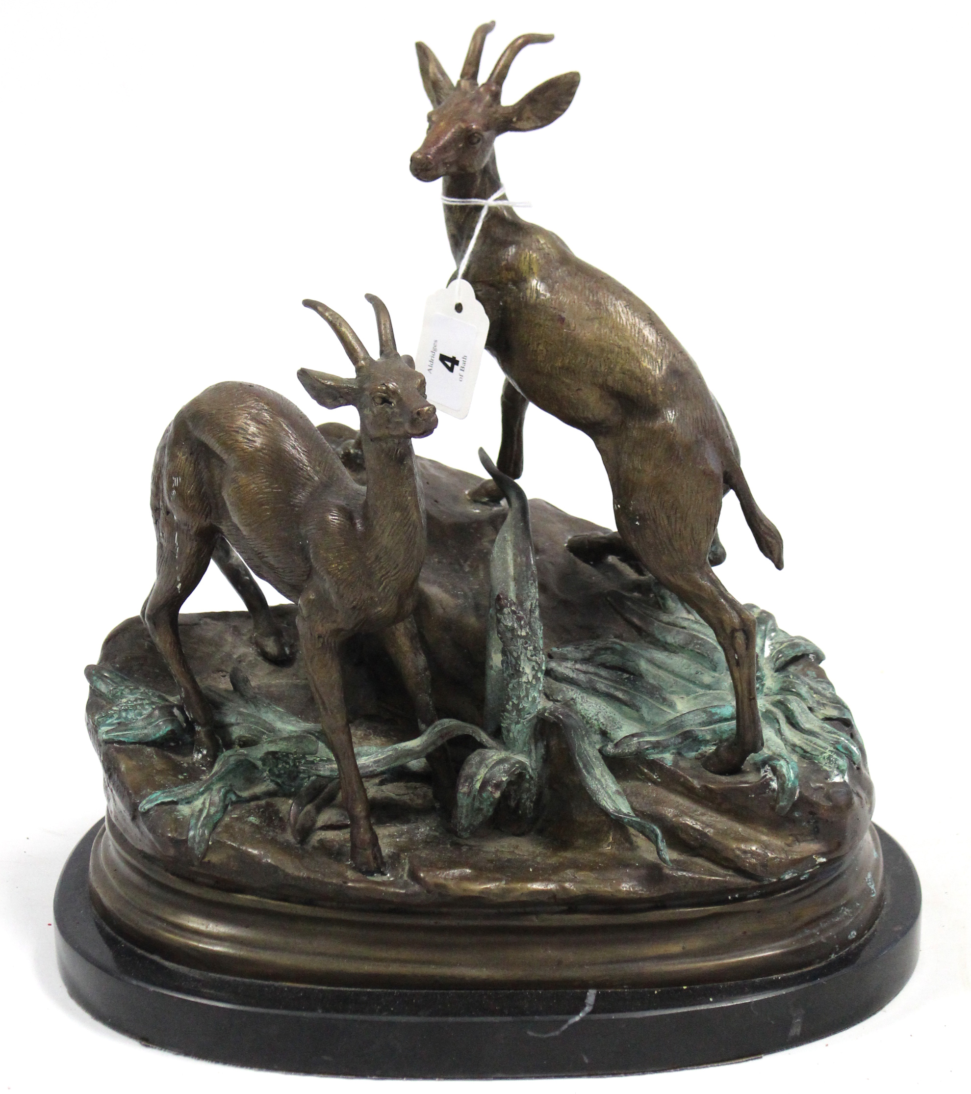 A bronzed sculpture in the form of two stags standing on foliate covered rocks, signed Moigniez, &