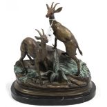 A bronzed sculpture in the form of two stags standing on foliate covered rocks, signed Moigniez, &
