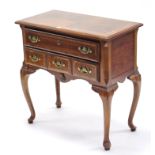 A reproduction walnut crossbanded small desk fitted two long graduated drawers, & on slender