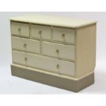 A cream painted pine low chest fitted with an arrangement of six drawers, & on plinth base, 42” wide