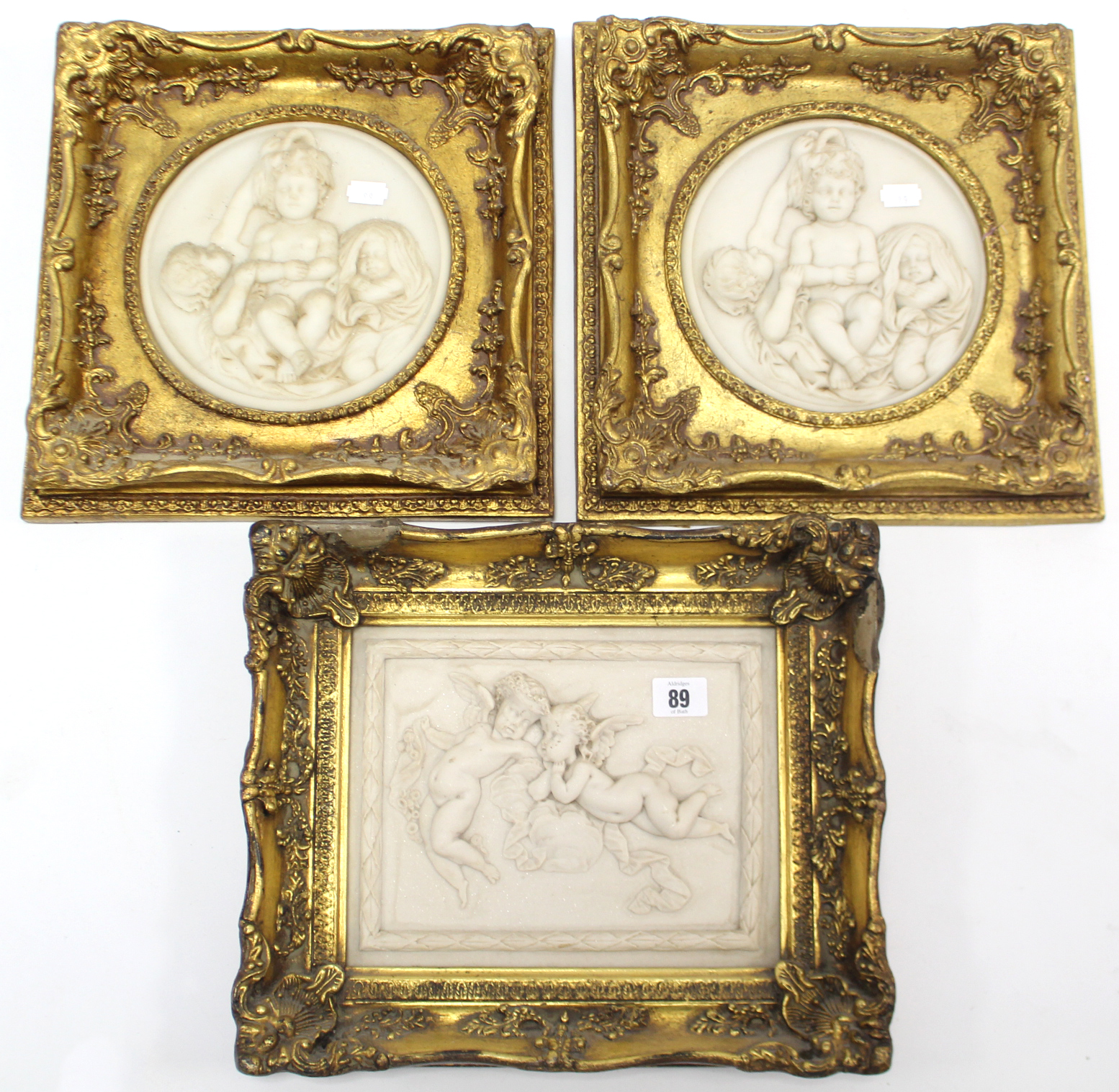 Three white composition plaques, each depicting cherubs & in gilt frames, (slight faults).