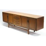 A 1970’s teak sideboard, fitted four long graduated drawers to centre flanked by cupboard to