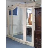 A large painted mahogany wardrobe with shaped cornice, panel door to centre with mirror door