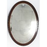 An Edwardian carved mahogany frame oval wall mirror inset bevelled plate, 36¾” x 25”.