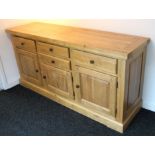 A light oak sideboard, fitted with an arrangement of four drawers above cupboards enclosed by