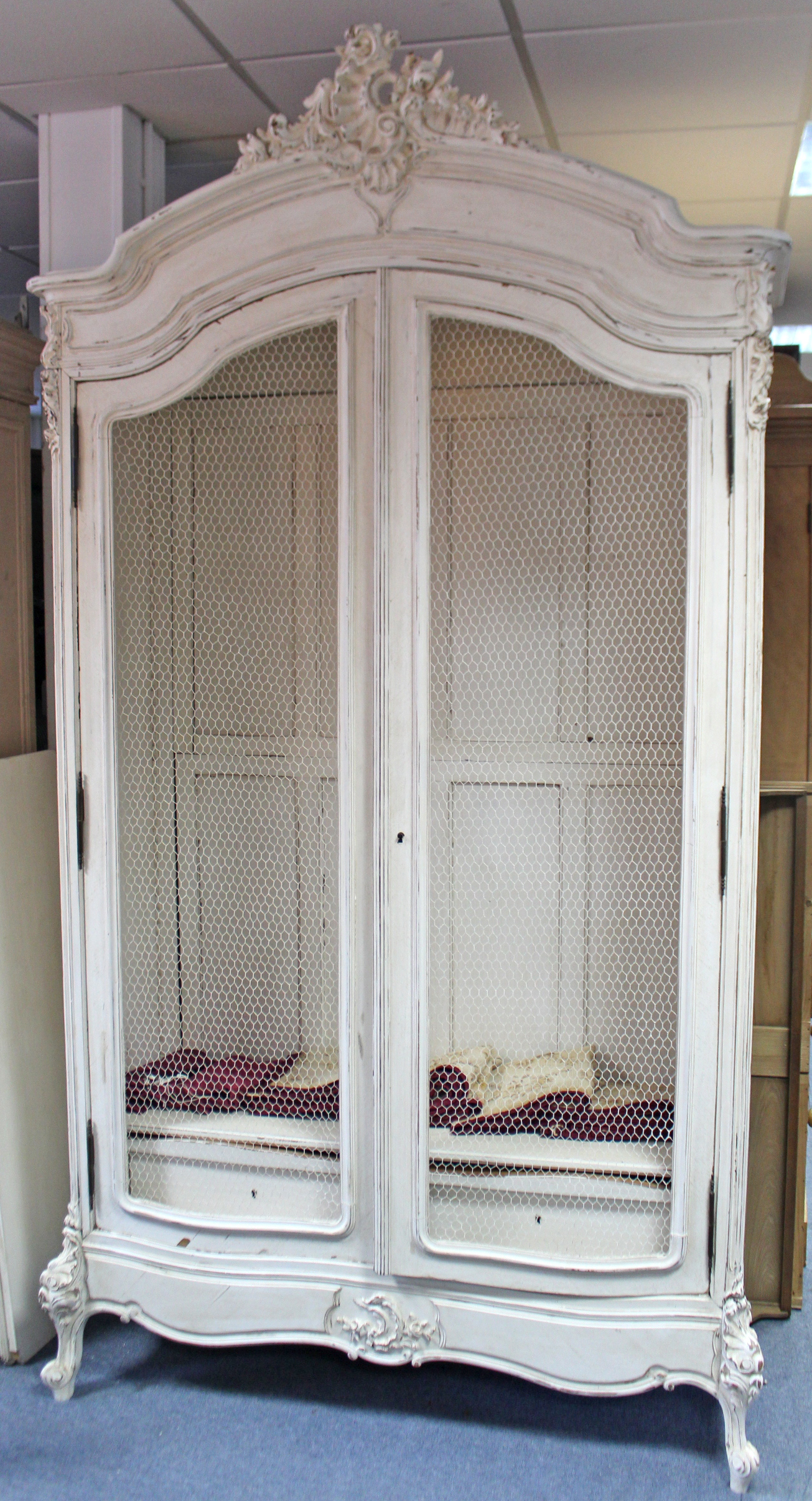 A continental-style white painted & carved wooden wardrobe with shaped cornice, enclosed by pair