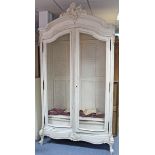 A continental-style white painted & carved wooden wardrobe with shaped cornice, enclosed by pair