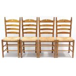 A set of four pine ladder-back kitchen chairs with woven-rush seats, & on round legs with spindle