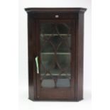 A 19th century inlaid-mahogany hanging corner cabinet, fitted three shelves enclosed by glazed door,