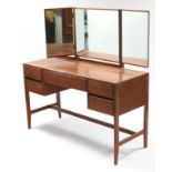 A 1960’s Heals teak knee-hole dressing table with triple-panel mirror to back, fitted five