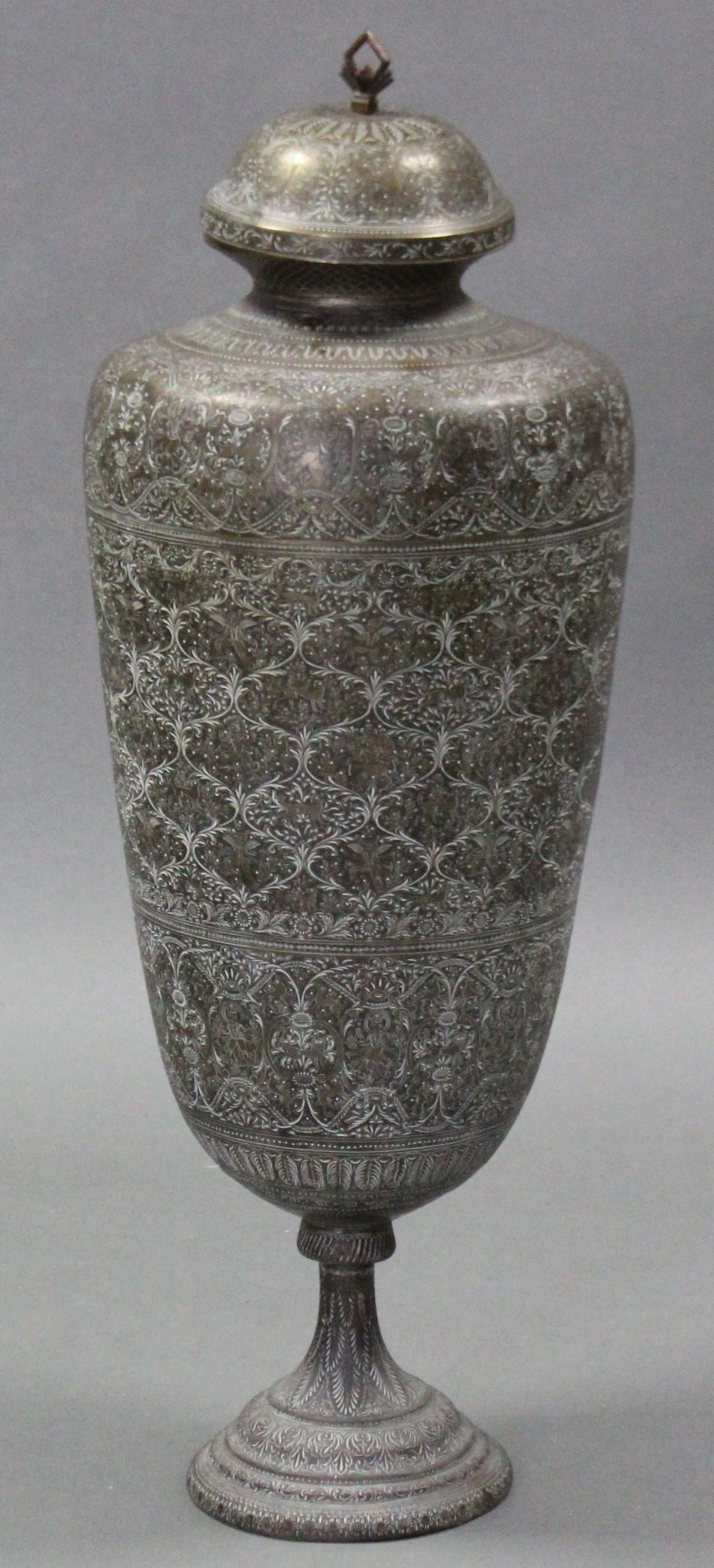 A large Islamic brass floor-standing vase, with tapered cylindrical body & domed cover, all-over