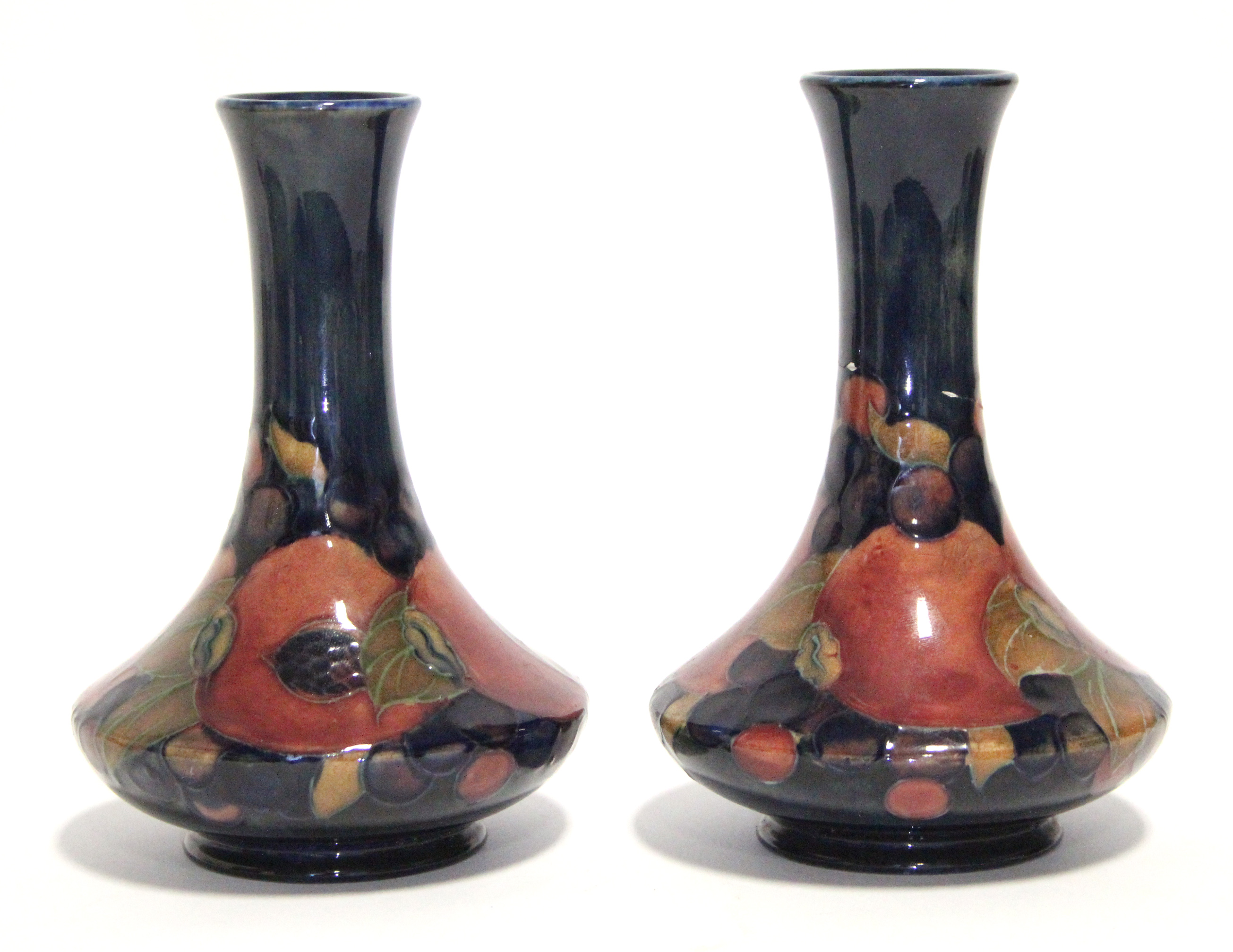 A pair of Moorcroft “Pomegranate” pattern squat round vases with tall narrow necks, blue painted