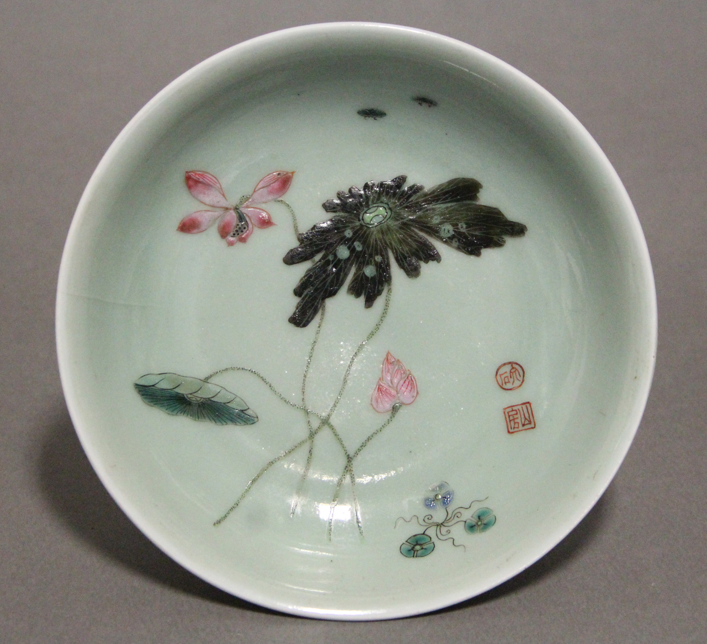 An 18th century Chinese porcelain saucer dish of celadon ground, painted with lotus flowers, leaves,