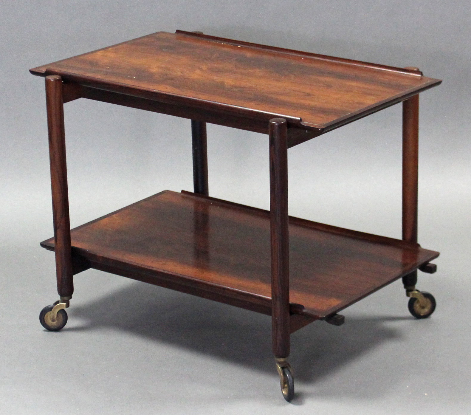 A mid-late 20th century Danish rosewood two-tier trolley, on cylindrical supports with brass