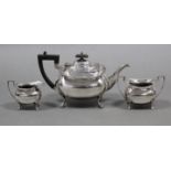 A three-piece tea service of compressed oblong form with cut-card rims, each on four curved feet.