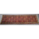A Persian corridor runner of deep red ground, with multi-coloured geometric design within multiple