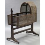 An early 19th century mahogany cradle, the arched canopy & sides with original caning, on turned end