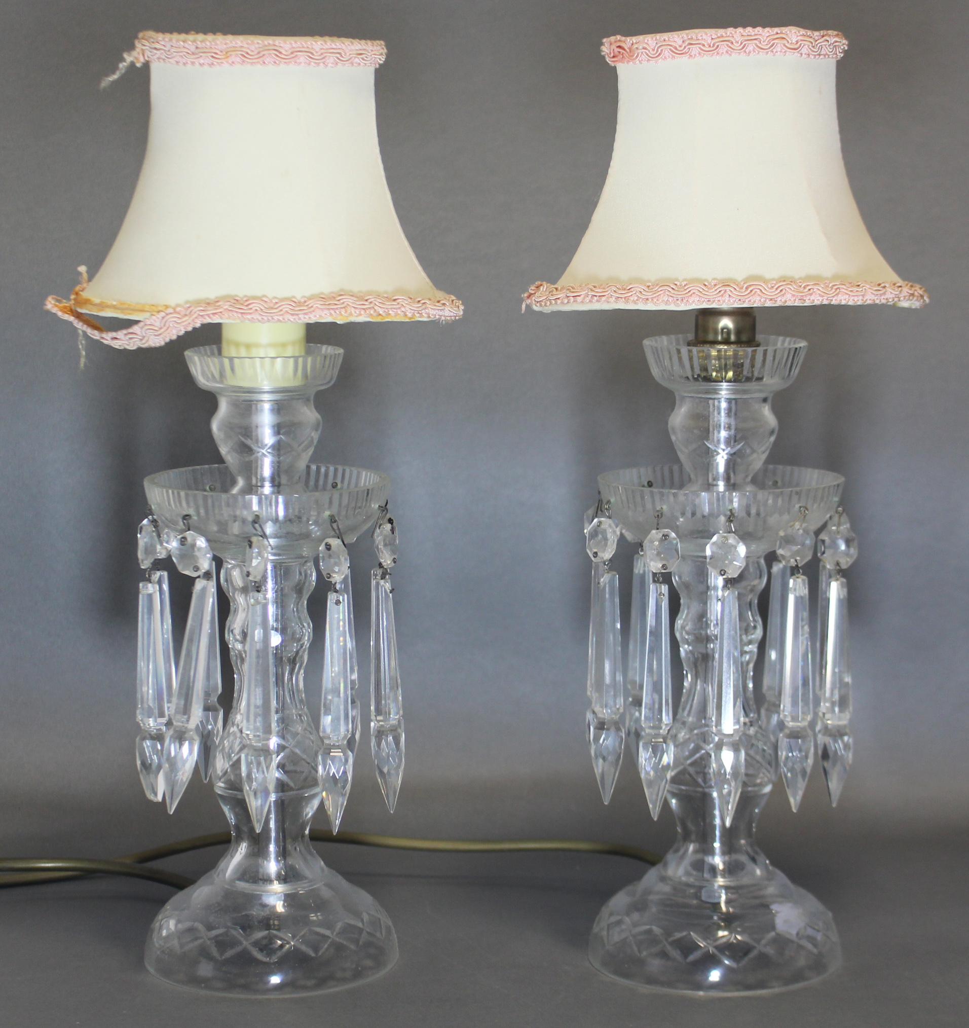 A pair of cut-glass table lamps in the form of candle lustres, the rounded drip-pans hung with prism