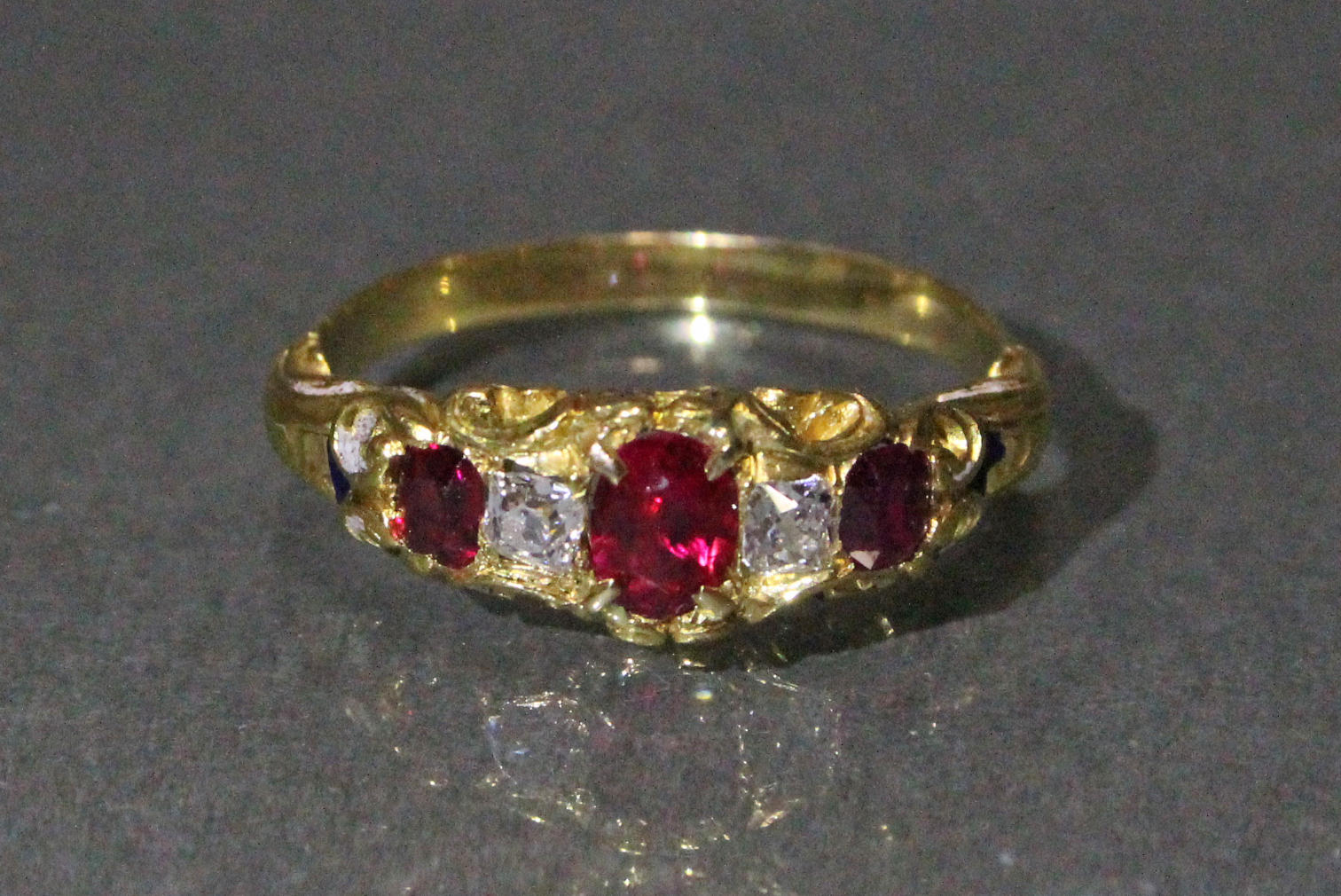 A Victorian un-marked gold ring set three oval rubies with cushion-shaped diamonds in between,