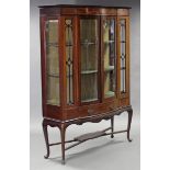 An Edwardian inlaid mahogany bow-front display cabinet, with glazed doors & sides enclosing three