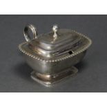 A George III silver mustard pot of compressed rectangular form, with gadrooned rim, ball finial to