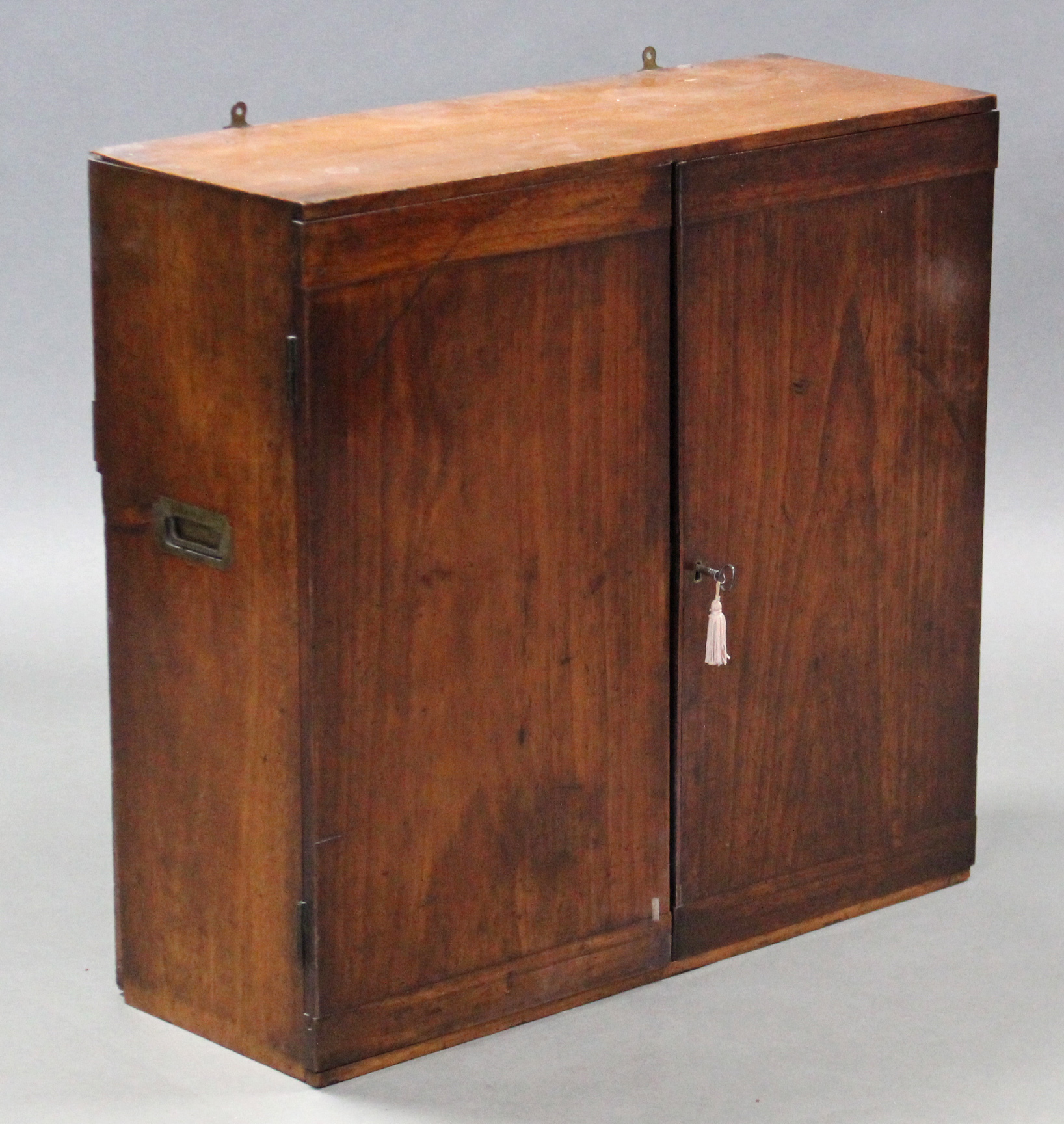 AN EARLY 19th century TEAK CAMPAIGN WALL-MOUNTED CABINET, fitted with an arrangement of five shelves