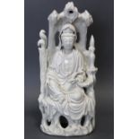 A CHINESE BLANCE-DE-CHINE FIGURE OF GUANYIN, seated in a grotto, wearing flowing robes & holding a