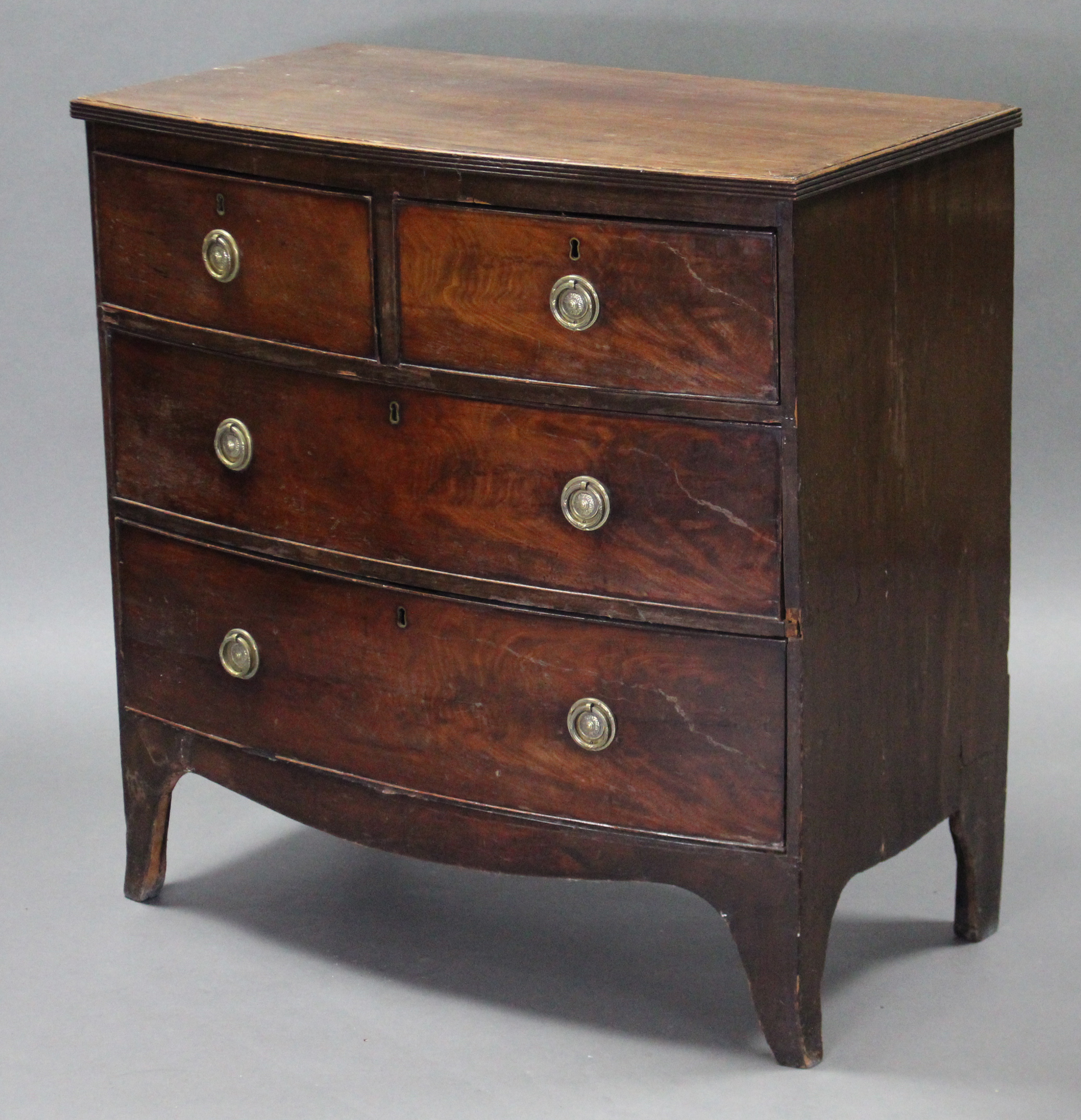 A George III mahogany bow-front chest fitted three graduated drawers with brass ring handles, on