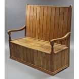 A late Victorian pine settle with tall back, open scroll arms, & three-plank box seat with central