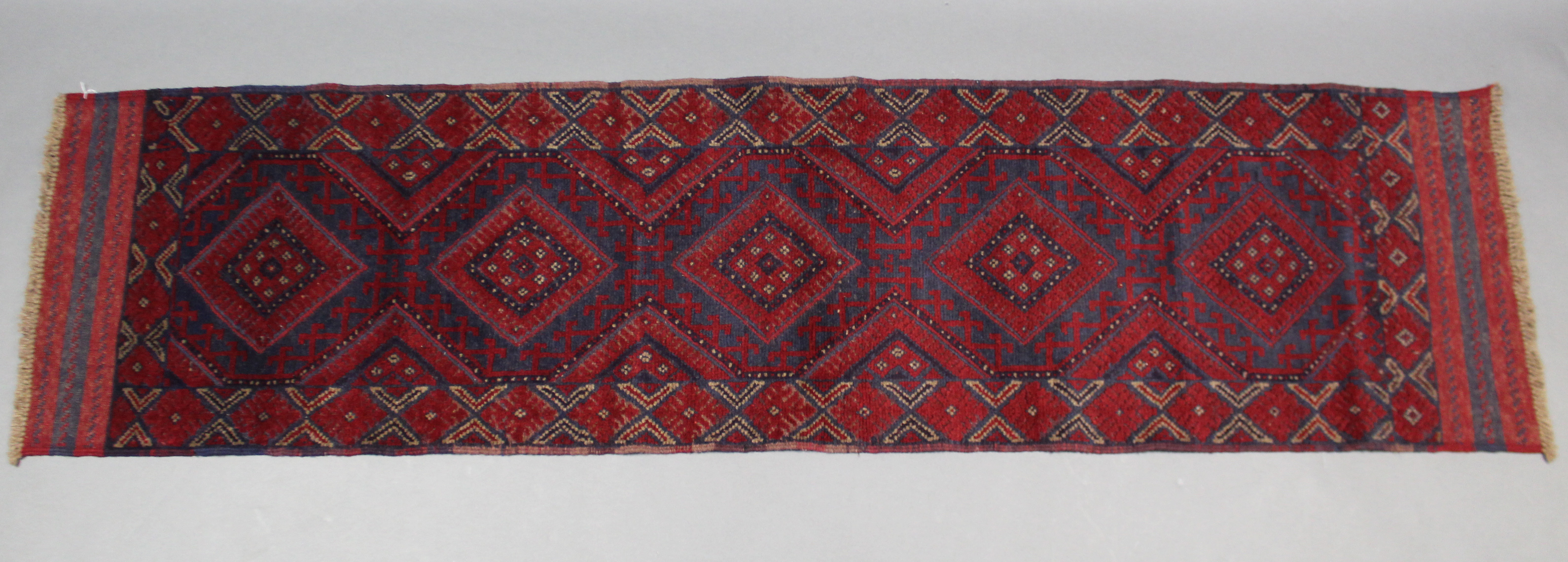 A Meshwari runner of deep blue, crimson, & ivory ground, with row of five lozenges in multiple
