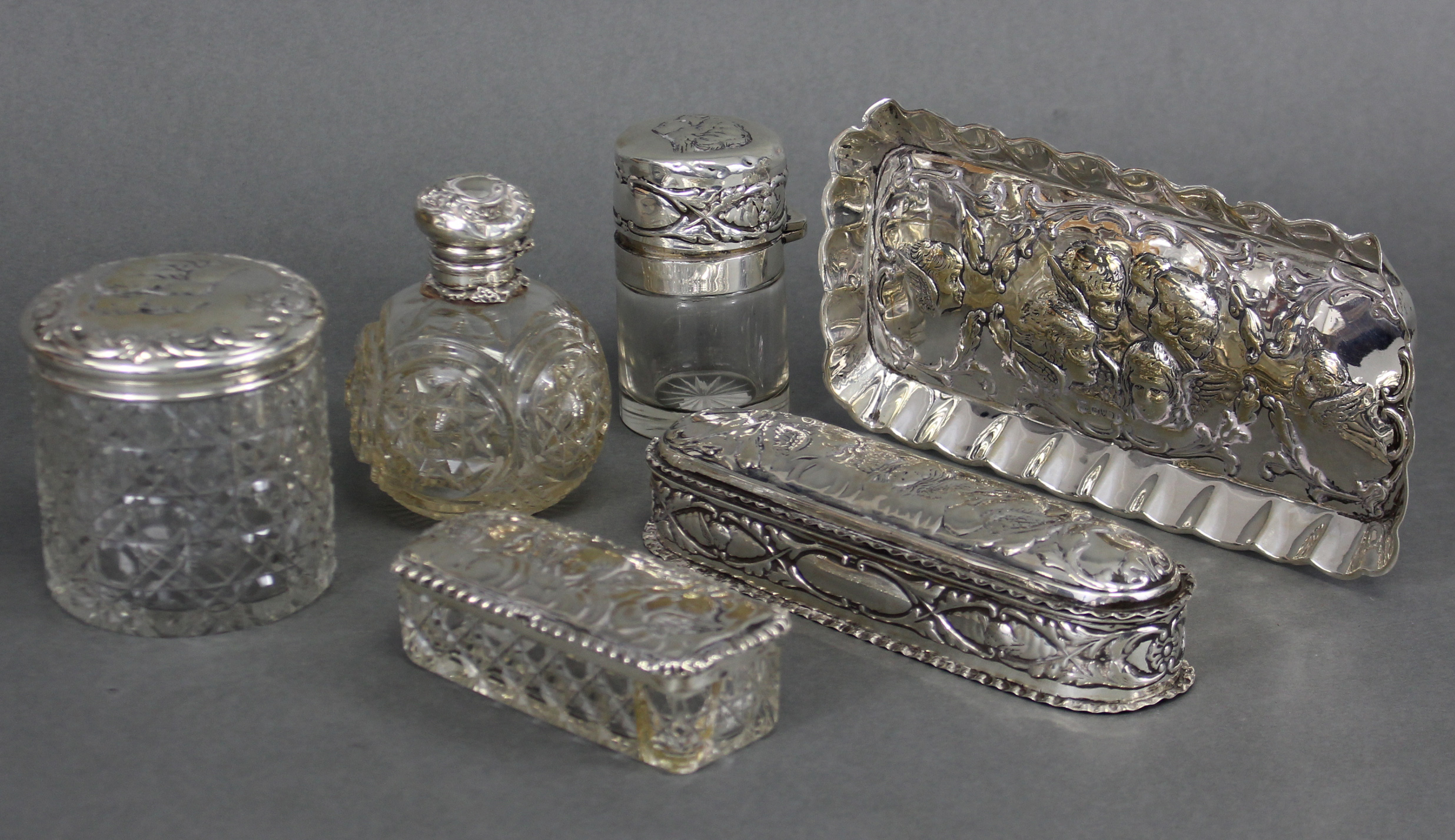 An Edwardian silver toilet set embossed with cherub masks, comprising: a rectangular pin tray, 7¾” x