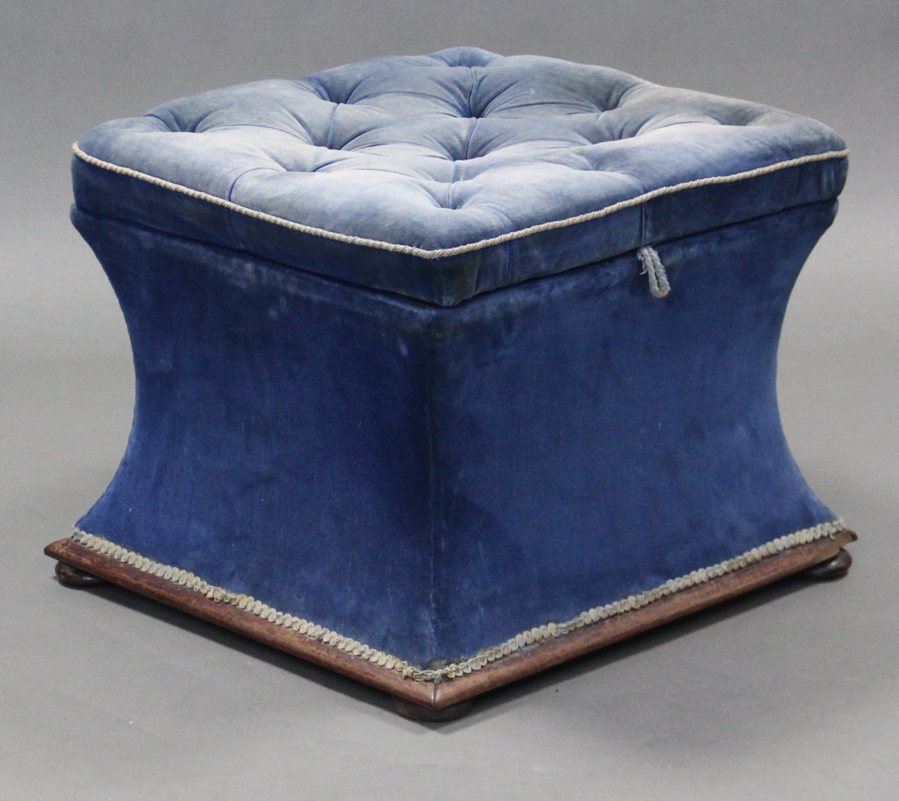 A Victorian square box ottoman with concave sides & buttoned seat, upholstered blue velour, & on bun