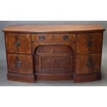 A SHERATON FIGURED MAHOGANY BOW-FRONT SIDEBOARD, fitted with a central frieze drawer