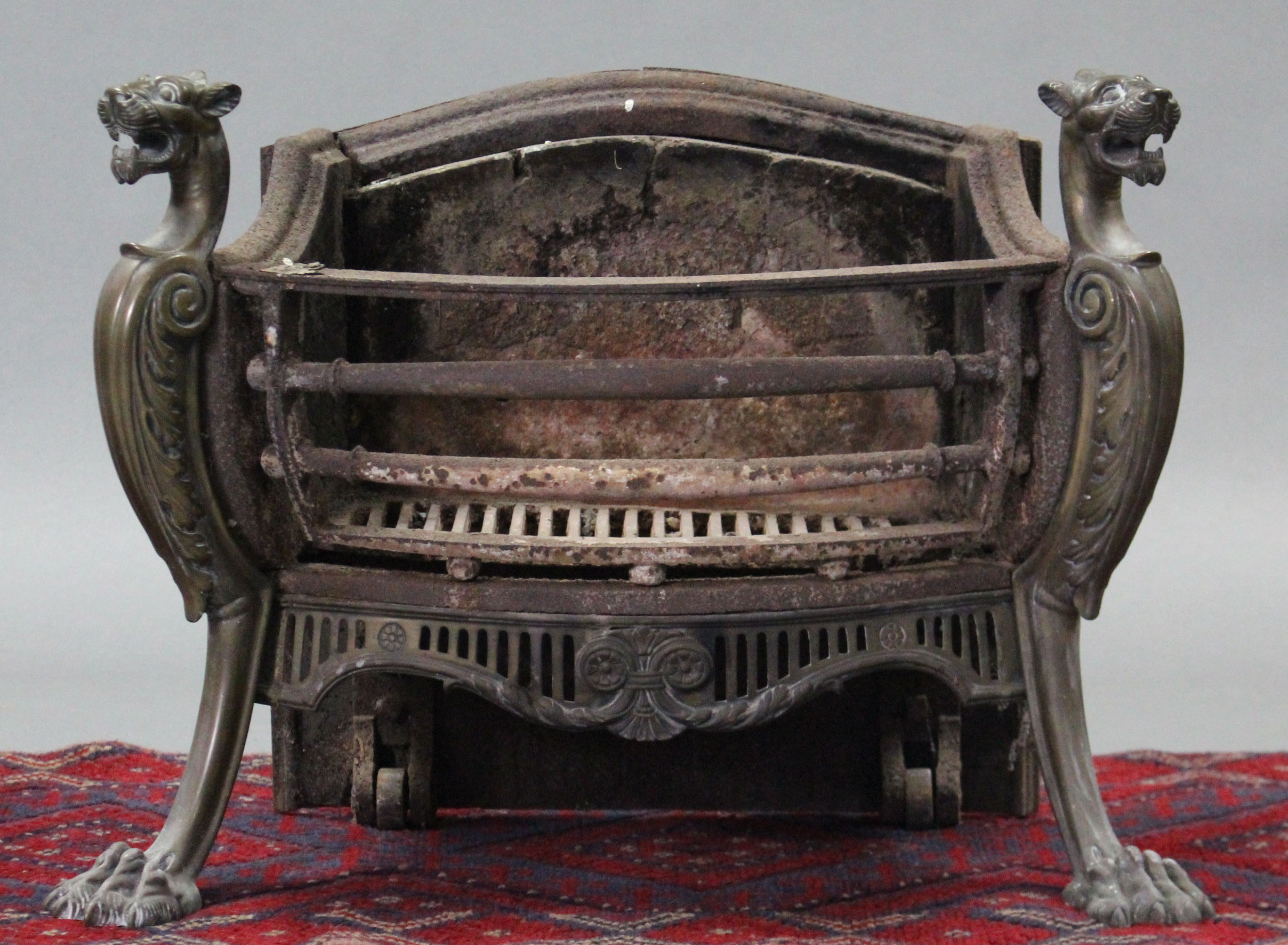 A 19th century cast-iron & brass fire grate with pierced foliate apron & acanthus scroll supports