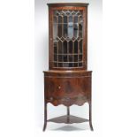 An early 19th century inlaid-mahogany standing corner cabinet, the upper part fitted three shaped