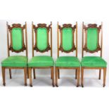 A set of four Edwardian carved oak dining chairs with padded seats & backs upholstered green velour,