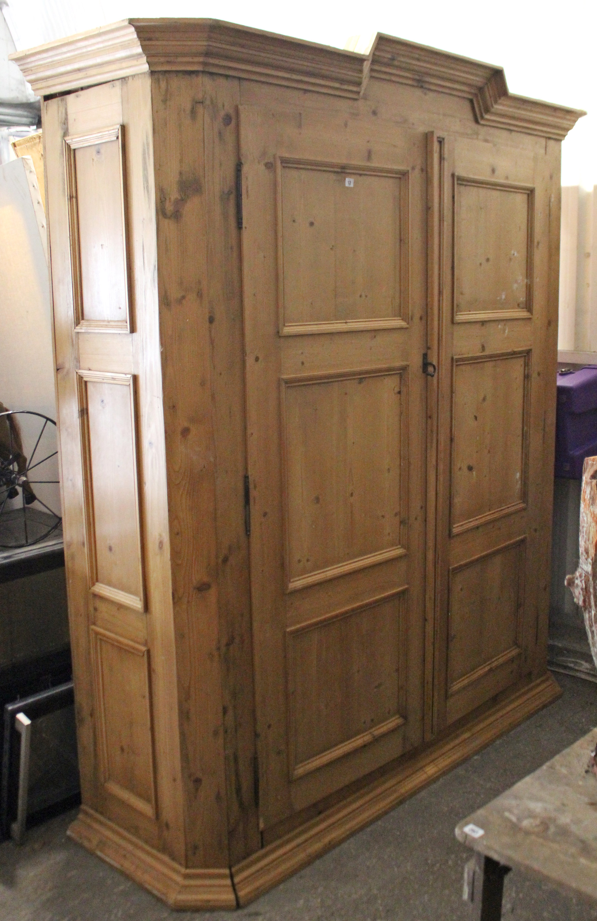 A continental-style large pine wardrobe with moulded cornice, enclosed by pair of panel doors, &