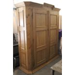 A continental-style large pine wardrobe with moulded cornice, enclosed by pair of panel doors, &