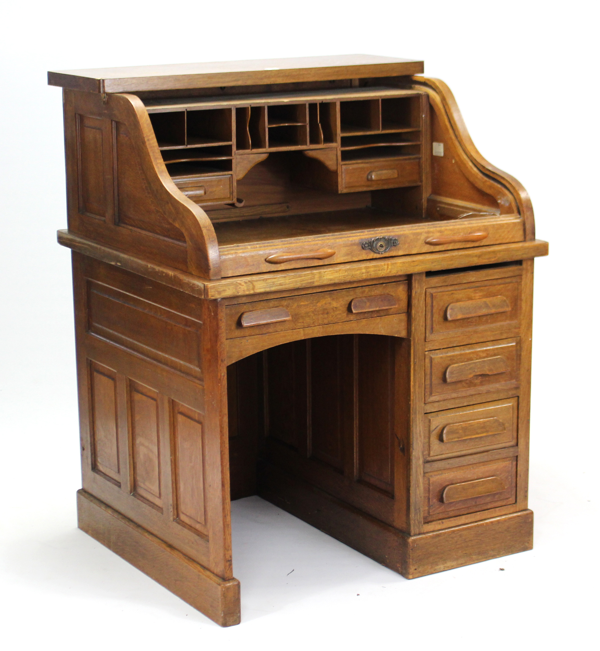 An early 20th century small oak knee-hole roll-top desk with fitted interior, enclosed by tambour