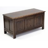 A reproduction oak blanket box with hinged lift-lid, linen-fold panel front, & on short square legs,