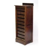 An Edwardian mahogany upright office cabinet fitted nine long drawers with hinged fall-fronts, &