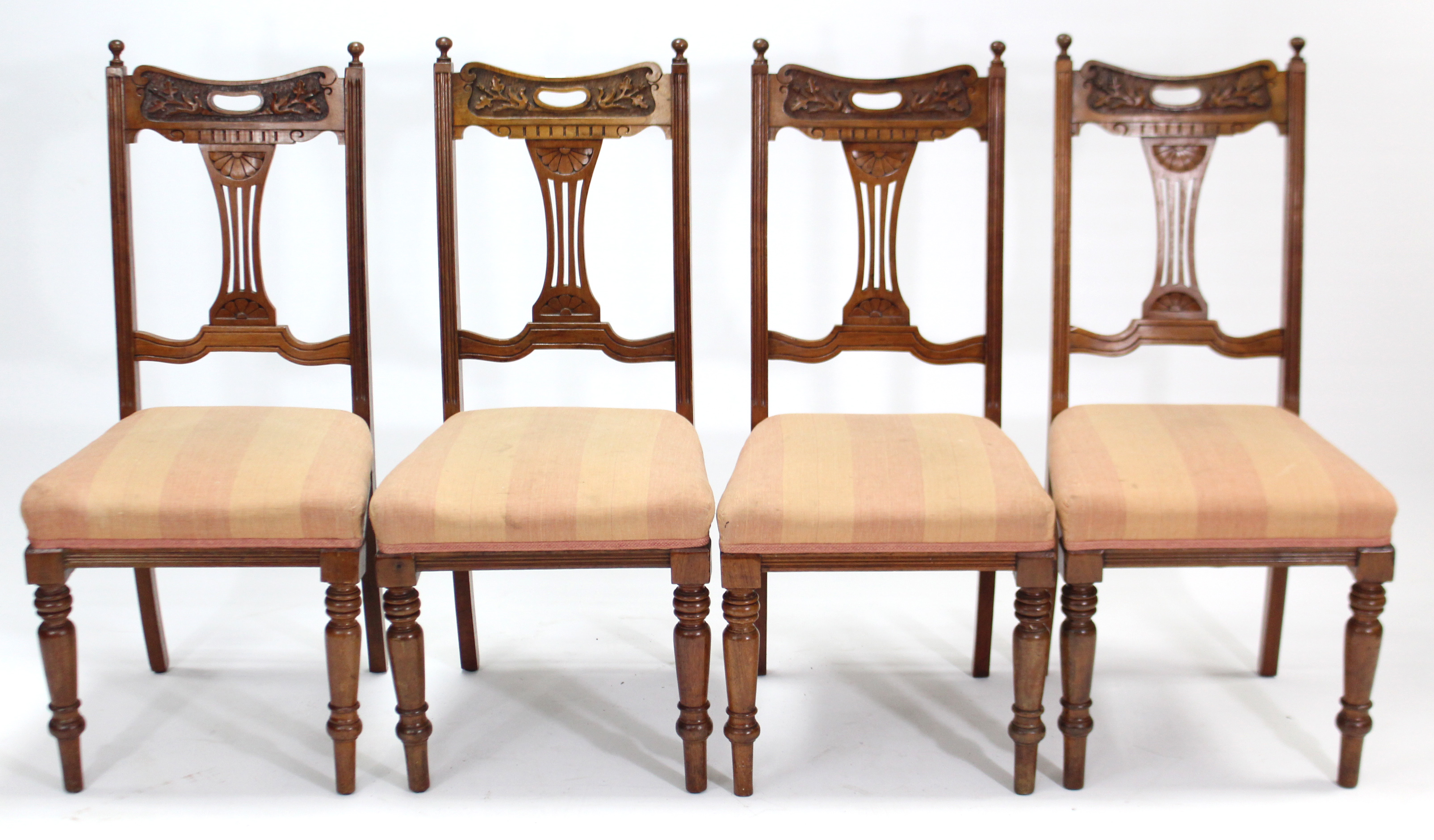 A set of four late Victorian carved walnut splat-back dining chairs with padded seats, & on turned