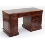 A reproduction mahogany pedestal desk inset gilt-tooled crimson leather, fitted with an