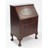 A mahogany bureau with fitted interior enclosed by fall-front & long drawer above cupboard