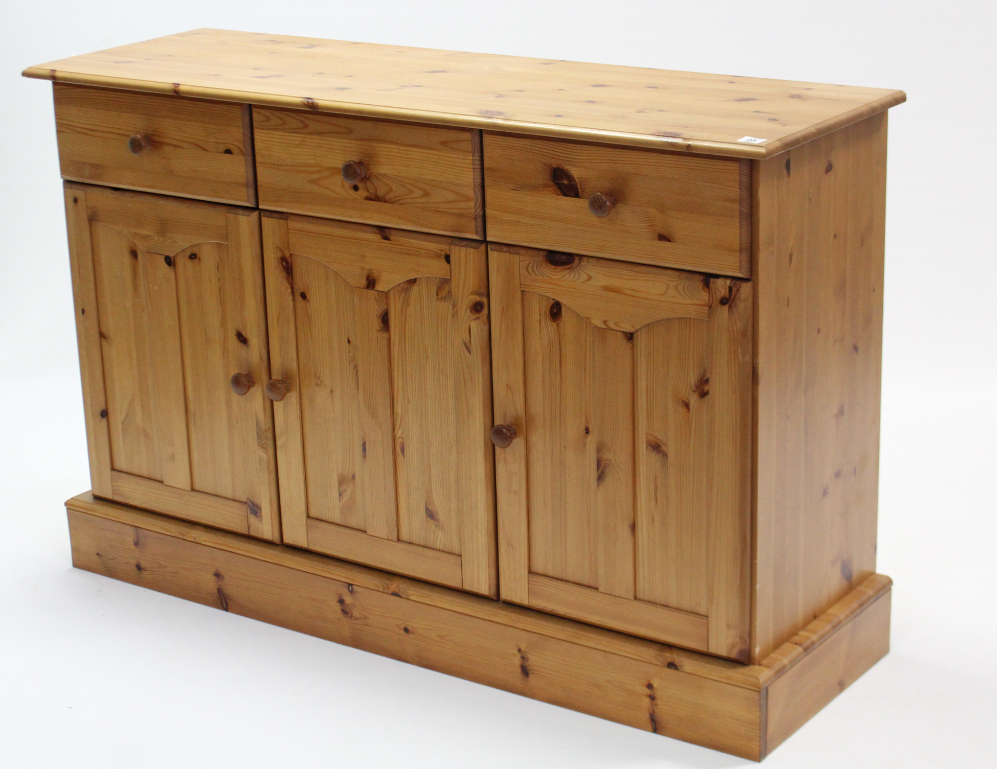A pine sideboard fitted three frieze drawers above cupboard enclosed by three panel doors, & on